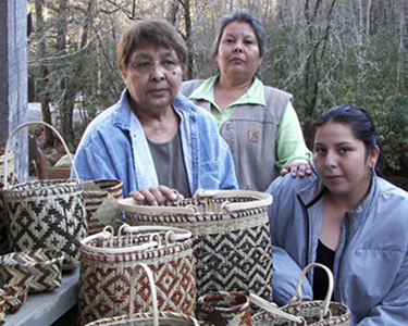 Three Native American women with handmade baskets.