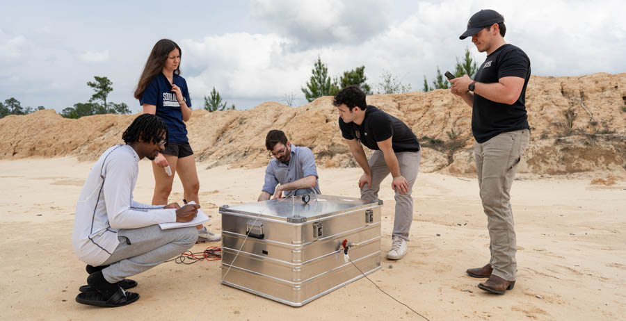 University of South ɬֱ students, from left, Devon Edinburgh, Paige Palazzo, Matthew Crump, Reed Turner and Luke Andress run though a series of tests on their senior research project at a firing range north of Mobile. 