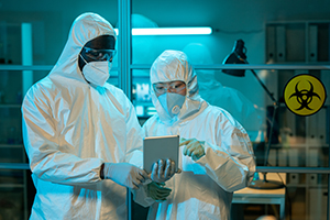 Two people in hazmat suits in a lab with biosafety sign behind them.